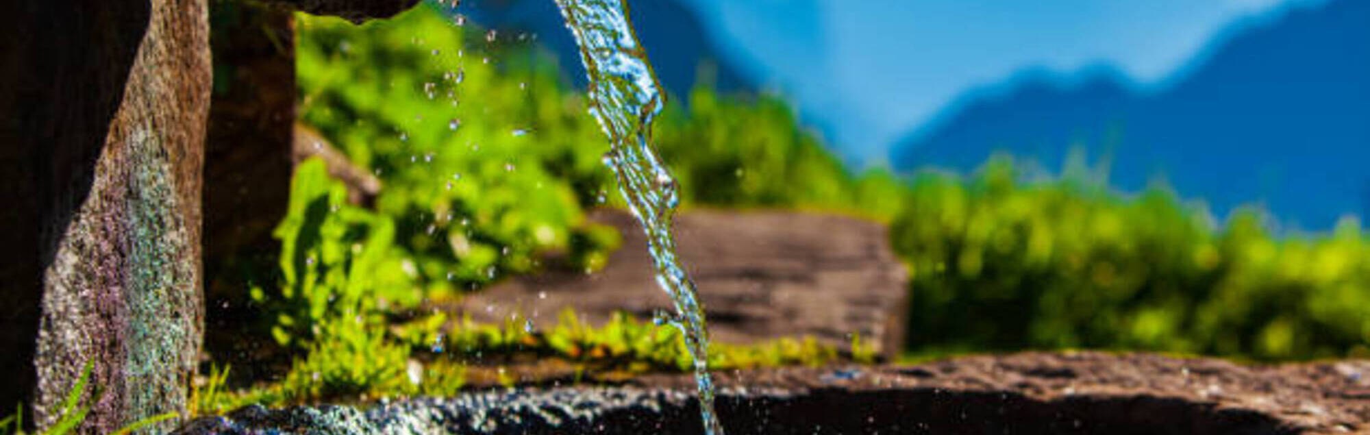 Water spring on Alps mountains background